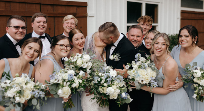 bride and groom kissing with wedding party looking on at joyful North Georgia wedding